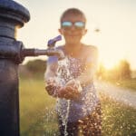 Un bambino a una fontanella in un parco urbano